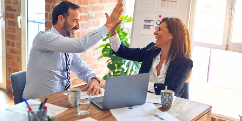 Team celebrating success with high five in office